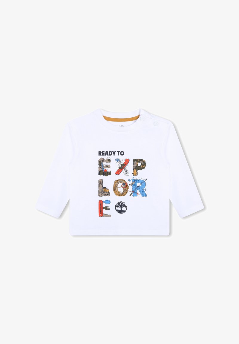 Camisa blanca de manga larga con un gráfico multicolor "LISTO PARA EXPLORAR", que incorpora diversas texturas y objetos ilustrados.