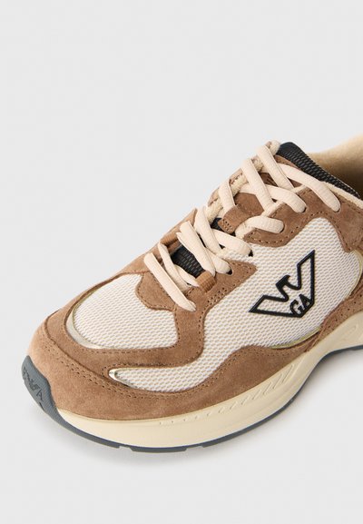 Brune mocka og beige mesh sneakers med kremfargede lisser, svarte detaljer og logo. Rund tå og polstret såle med teksturert mønster.