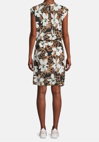 Blommönstrad klänning i mörka toner med vita liljor och bruna detaljer. Kort ärm, figurnära midja, knä-längd och lättviktsmaterial.