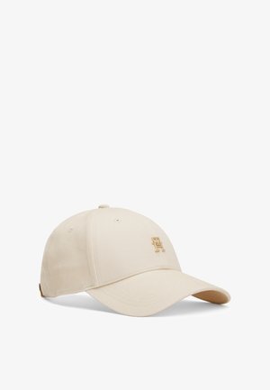 Beige bomull cap med bøyd skjerm, med en gullbrodert logo på forsiden og ventilasjonsøyler på kronen.