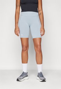 Lys blå idrettsshorts med glatt tekstur og elastisk midjebånd med "Under Armour" merke. Sammen med grå joggesko og hvite sokker.