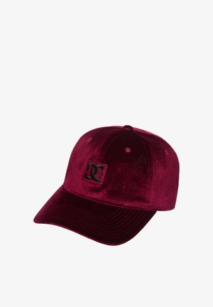 Dunkelrotes Baseball-Cap aus Samt mit einem schwarzen DC-Logo-Patch auf der Vorderseite und gestickten Belüftungsösen auf der Krone.