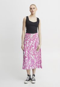 Top negro de canalé combinado con una falda midi de patrón abstracto en rosa y blanco. La modelo lleva zapatillas altas negras.