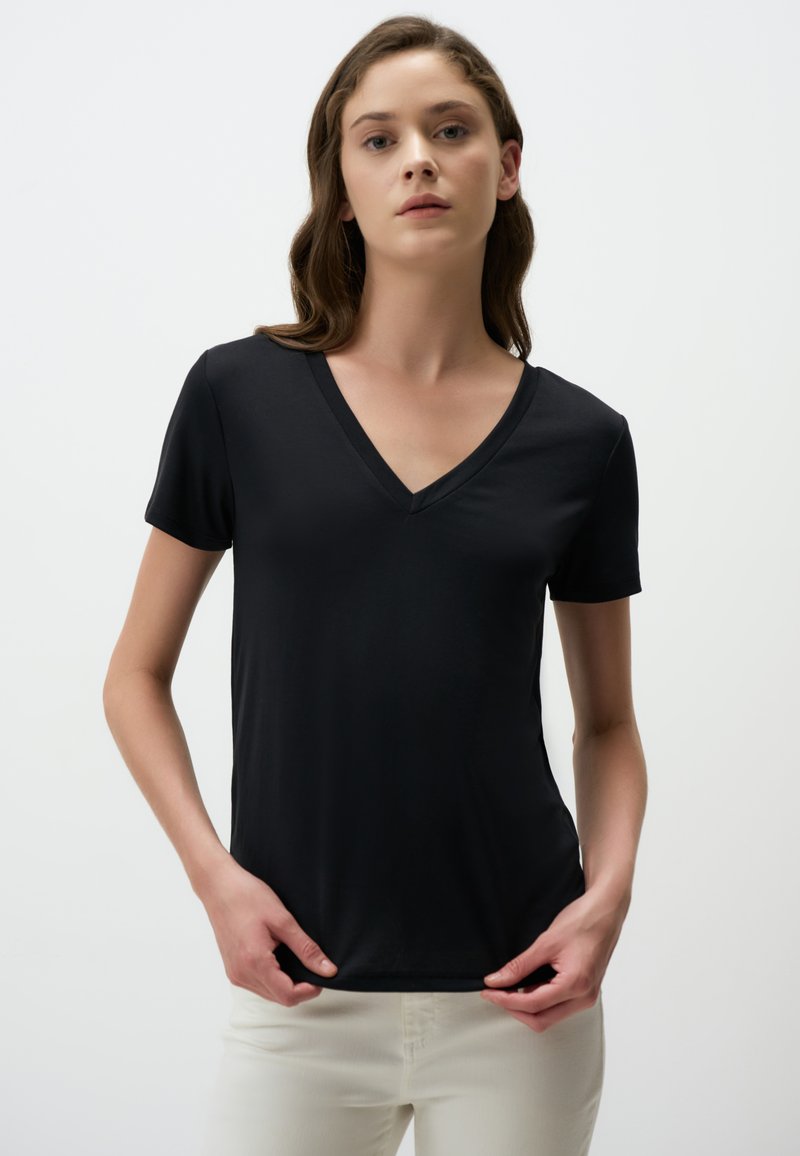 Czarna krótka koszulka z dekoltem w serek, wykonana z gładkiego materiału, o dopasowanej sylwetce i subtelnych detalach na bocznych szwach.