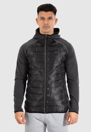 Schwarze Zip-Jacke mit gestepptem Vorderteil und glatten Ärmeln, mit Kapuze und kontrastierenden Nähten für zusätzlichen Designakzent.