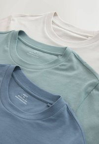 Trīs muskuļveida piegriezuma T-krekli no mīkstas kokvilnas: balts, gaiši tirkīza un tumši tirkīza. Katram kreklam ir apaļš kakla izgriezums un smalkas šūšanas detaļas.