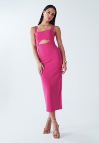 Robe ajustée mi-longue rose vif, avec un décolleté carré et un détail découpé, confectionnée en tissu côtelé, avec des bretelles fines.