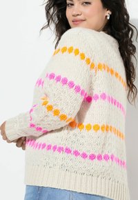 Striktrøje i off-white med livlige pink, orange og gule vandrette striber. Løs pasform med ribkanter ved håndled og nederkant. Strukturmønster.