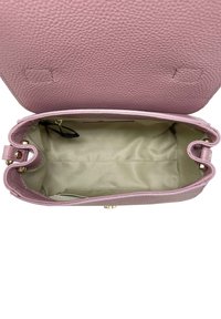 Wnętrze torebki z różowej skóry o fakturze łupka, z beżową podszewką, z złotym zapięciem i dwoma okrągłymi uchwytami. Brak widocznych kieszeni lub oznaczeń.