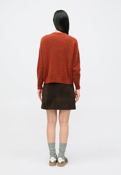 Roostevärvi kootud kampsun, pruun seemisnahast lühike seelik, hallid soonilised sokid, rohelised ja valged tossud. Sile tekstuur, igapäevane disain.