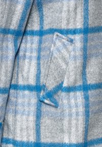 Grauer und blauer karierten Wollstoff mit weicher Textur, mit einem aufgesetzten Taschen eine Seite des Materials verziert.