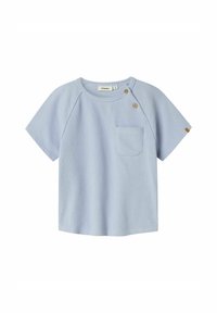 Lyseblå t-skjorte med korte ermer og rund hals, en enkelt brystlomme, og to treknapper på skulderen. Strukturert stoff.