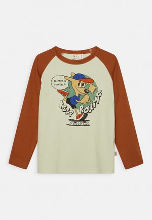 Langärmliges cremefarbenes Hemd mit braunen Ärmeln, das einen Cartoon-Hund zeigt, der Skateboard fährt, mit dem Spruch "Glaub an dich selbst!" und dem Text "Keep Rolling".
