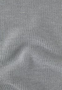 Tessuto grigio chiaro con texture e motivo a righe, che mostra cuciture visibili e un aspetto soffice e intrecciato. Ideale per abbigliamento o tappezzeria.