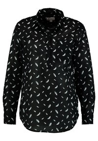 Chemise noire à manches longues avec un col, ornée d'un motif de plumes blanches. Comprend une poche poitrine et une coupe décontractée.