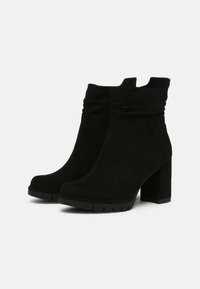 Bottines en suede noir avec un design froncé, des talons blocs et des semelles texturées. Elles présentent un bout arrondi et des coutures lisses.