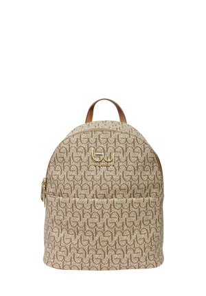 Sac à dos beige et marron à motifs avec une poignée supérieure, une poche zippée à l'avant, et un emblème logo en métal doré sur fond blanc.
