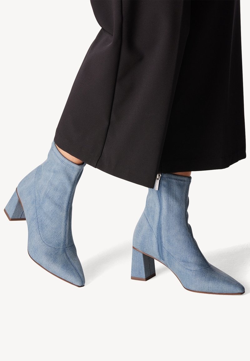 Bottines en denim bleu clair à talons blocs et fermetures éclair latérales, portées avec un pantalon noir court.