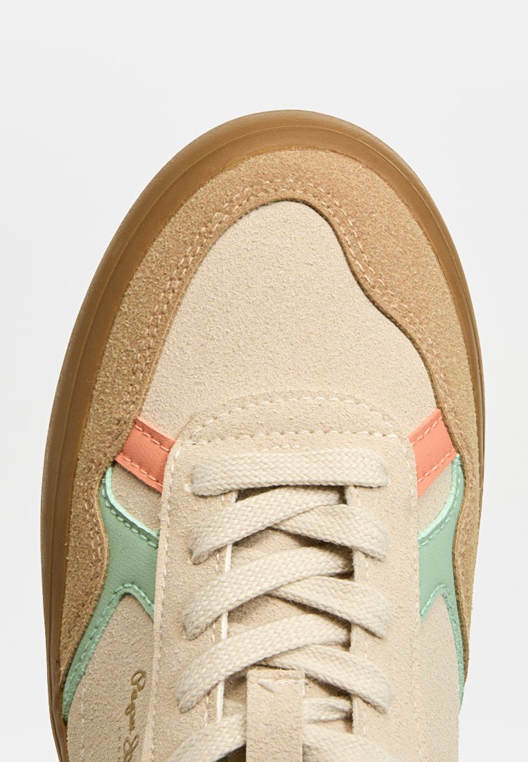 Zapatilla beige con parte superior de ante, con acentos en verde y coral, cordones planos y suela de goma. Materiales suaves y texturizados.