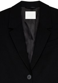 Must Black ülikond, millel on sile kangas, revääriga krae, ühe nupuga kinnitamine ja peidetud sisemine tasku, mis lisab funktsionaalsust.