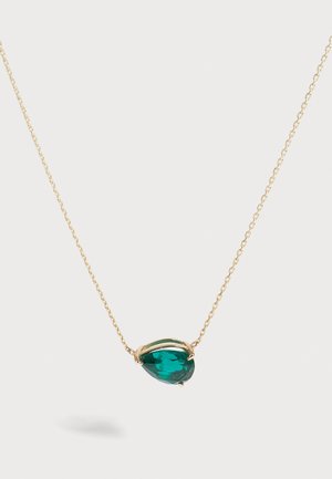 Collier délicat en chaîne d’or avec un pendentif en pierre précieuse vert foncé en forme de goutte, centré sur un fond clair uni.