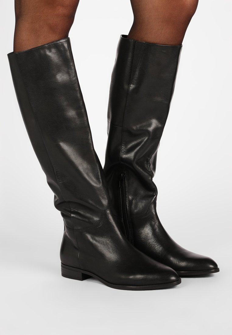 Bottes en cuir noir au genou avec un bout pointu, un talon plat et une fermeture éclair sur le côté. Le matériau a une texture lisse avec un léger éclat.