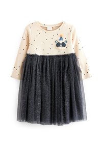 Robe crème à manches longues avec des pois noirs, ornée d'un patch en forme de visage de panda et d'une jupe en tulle noir avec des paillettes dorées au bord.