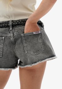 Denim short in vervaagd zwart met een versleten zoom en twee achterzakken. Voorzien van een geweven zwarte riem en een Superdry-label op de zak.