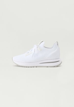 Fehér sportcipő texturált kötött felsőrésszel, lapos fűzőkkel és ezüst színű kiegészítőkkel a talpon. Tartós gumi talppal rendelkezik.