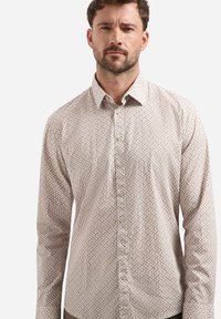 Heren overhemd met knopen in lichtbeige met een geometrisch patroon in roze en groen. Voorzien van een kraag en lange mouwen, gemaakt van soepel stof.