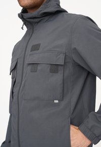 Grau utility-Jacke mit Kapuze, ausgestattet mit zwei vorderen Klappentaschen, einem Reißverschluss und elastischen Bündchen. Glattes, leichtes Material.