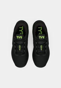 Zapatillas deportivas negras con parte superior de malla, diseño texturizado, puntera redonda y acentos verdes contrastantes en el logotipo y la plantilla.