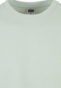 T-shirt vert clair col rond avec une étiquette de la marque Urban Classics visible en taille medium à l'intérieur du col.