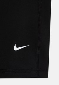 Mustad mustikud ketsid venivast kangast sujuva tekstuuriga. Omavad valget Nike'i logo ja nähtavat musta õmblust õmbluste kohal.