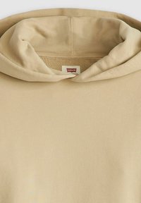 Felpa con cappuccio beige dalla texture morbida, con scollo rotondo e dettagli a coste. Etichetta del marchio visibile nella zona del collo.