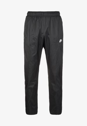 Pantalon de sport noir en nylon avec taille élastique, coupe ample et petit logo blanc Nike sur la cuisse droite.