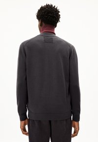 Dunkelgrauer Sweatshirt mit hohem Kragen und weinrotem Akzent. Stricktextur, gerippte Bündchen und Saum sowie ein rechteckiger Rückenpatch.