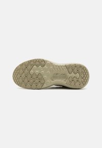Semelle de chaussure avec une texture antidérapante présentant des motifs hexagonaux et en losange ; couleur beige atténuée ; marque "V3R0CUSH" affichée de manière proéminente.