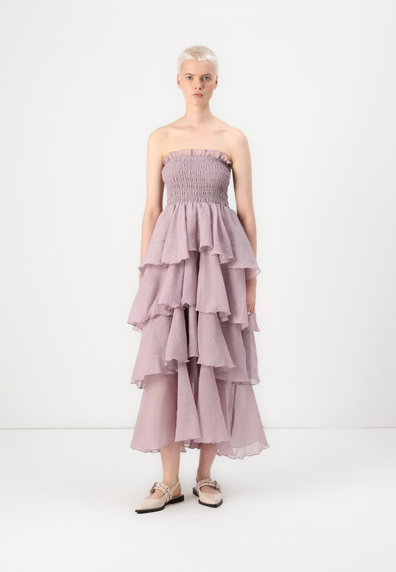 Robe lavande sans bretelles avec un corsage smocké et plusieurs volants empilés. Tissu léger, ourlet à mi-cuisse et texture douce.