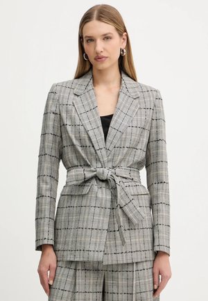Blazer grigio a quadri realizzato in tessuto testurizzato. Caratterizzato da un rever a risvoltini, una cintura da annodare in vita e una vestibilità sartoriale. Dettagli con motivo a griglia nera.