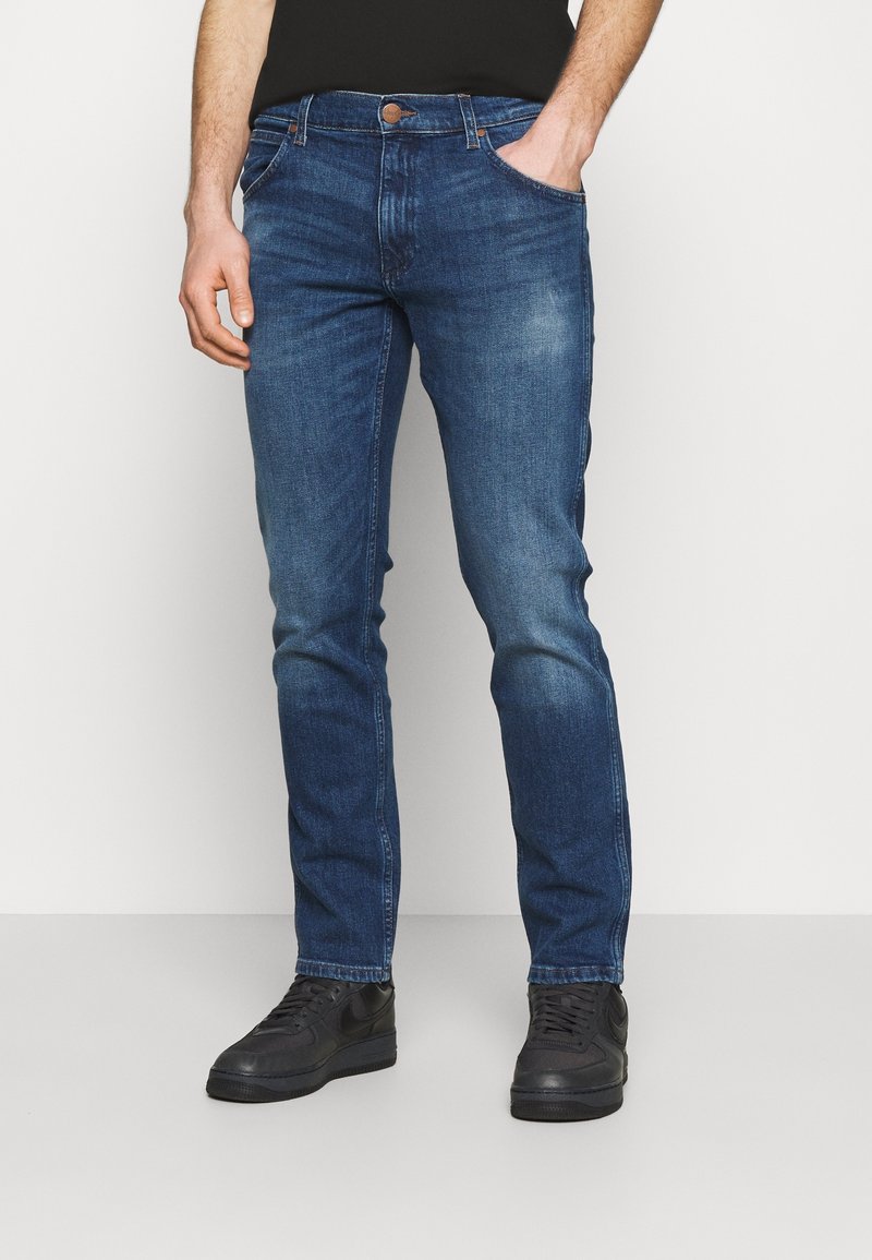 Mörkblå denimjeans med slim fit, med en klassisk femfickedesign och en enkel knappstängning vid midjan.