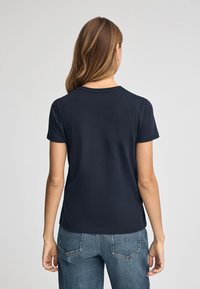 Granatowa bawełniana koszulka z okrągłym dekoltem. Krótkie rękawy i luźny krój. Gładka tekstura bez widocznych wzorów czy akcentów.