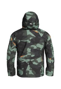 Grön camouflagedress med huva, med orange detaljer och en strukturerad tygkvalitet. Designen inkluderar olika nyanser av grönt och svarta mönster.