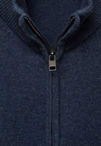 Pullover en maille bleu marine avec un col haut et une fermeture éclair noire. Texture douce avec des bords côtelés le long du col et de l'ouverture de la fermeture éclair.
