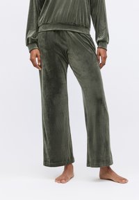 Velvet loungewear set in olijfgroen, met wijde pijpen en een relaxed fit. Soepele textuur, met een elastische tailleband en manchetten.