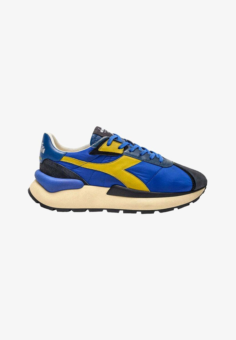 Sneaker atletico blu e giallo realizzata con materiali in pelle e scamosciata, forma arrotondata, suola spessa e accenti a contrasto in nero sulla punta e sul tallone.