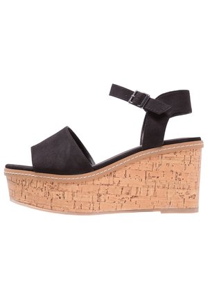 Černá semišová wedge sandála s korkovou platformou, kotníkovým páskem a stříbrnou přezkou, boční pohled na bílém pozadí.