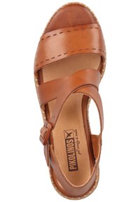 Brown leather sandal with cross straps and adjustable buckle, featuring a comfortable footbed and stitched detailing around the sole.