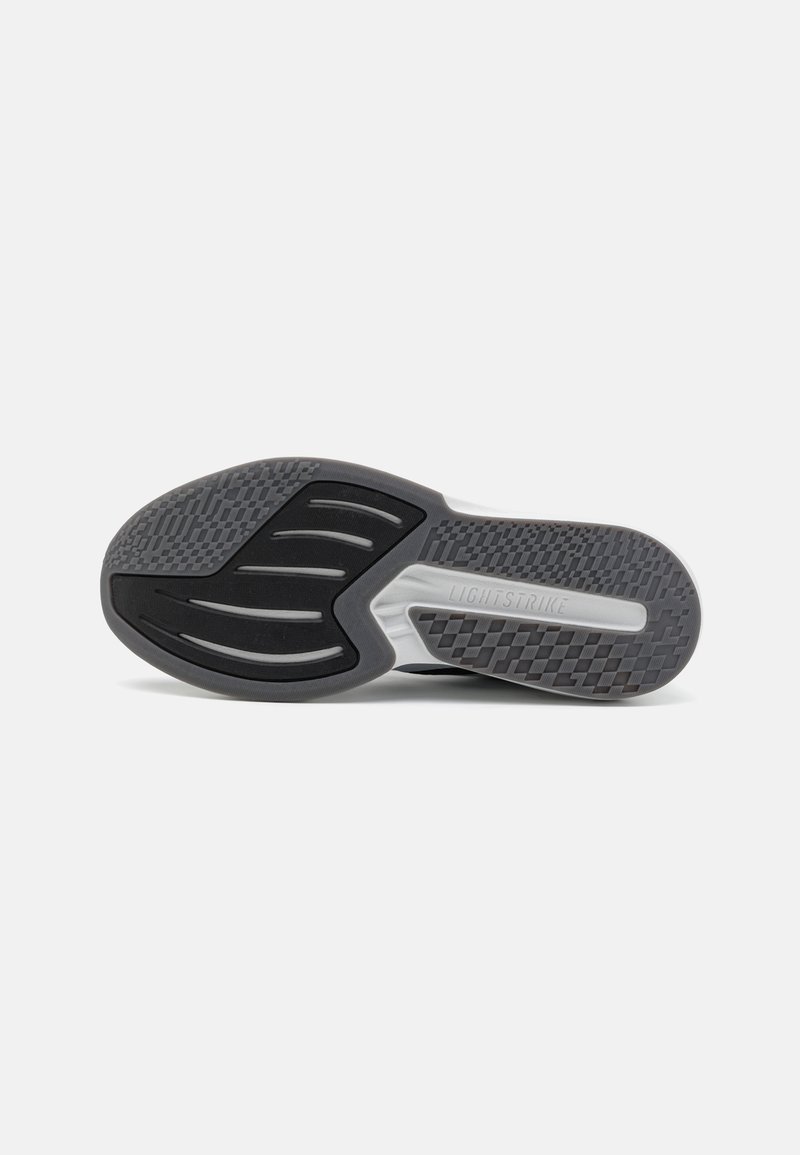 Suela de zapato de goma negra con un patrón texturizado, que presenta ranuras para el agarre y la palabra "LIGHTSTRIKE" grabada en el lateral.