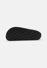 Svart sneaker sula med ett strukturerat diamantmönster, släta kanter och en lätt kilform för ökad höjd.
